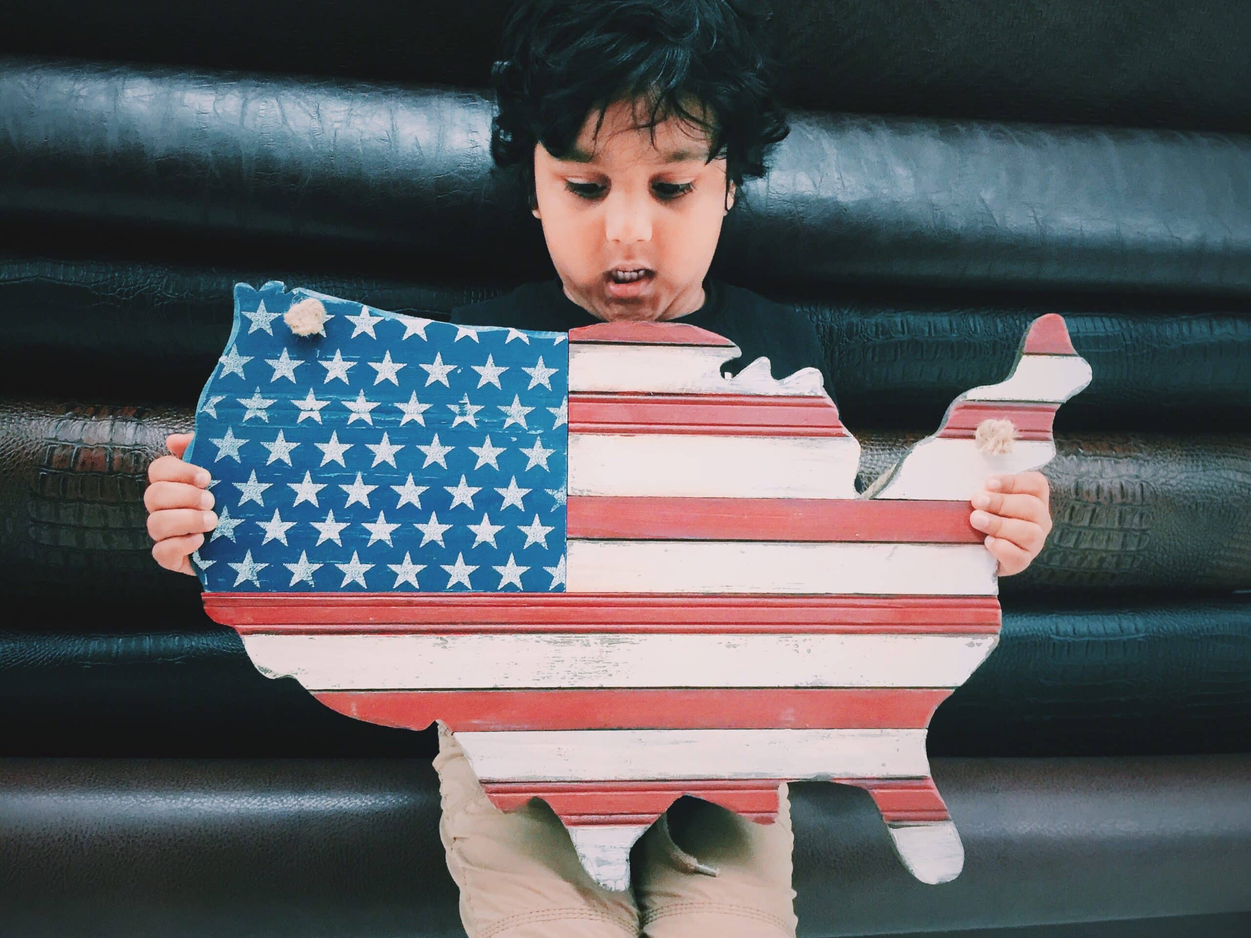 How to calculate cost of living: boy holding a wooden outline of the US