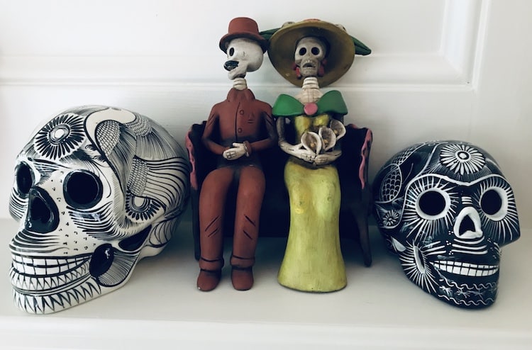 Día de los Muertos traditions: 2 painted skulls beside 2 seated skeletons
