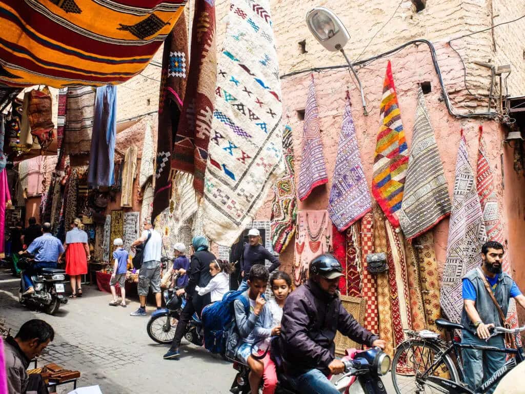 People walking and driving along a market in Morocco