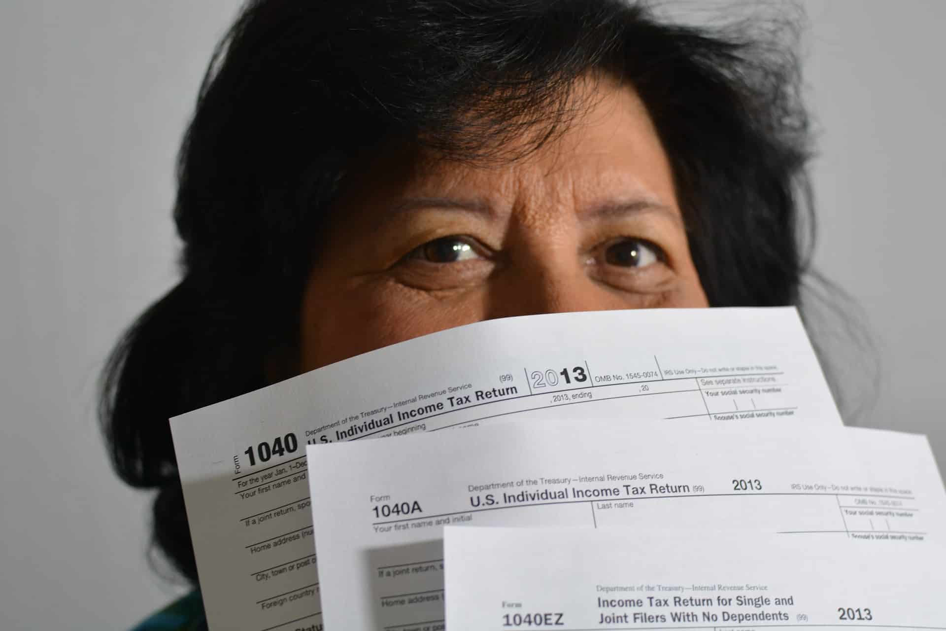 Le visage d'une dame à moitié caché sous les formulaires de déclaration d'impôts