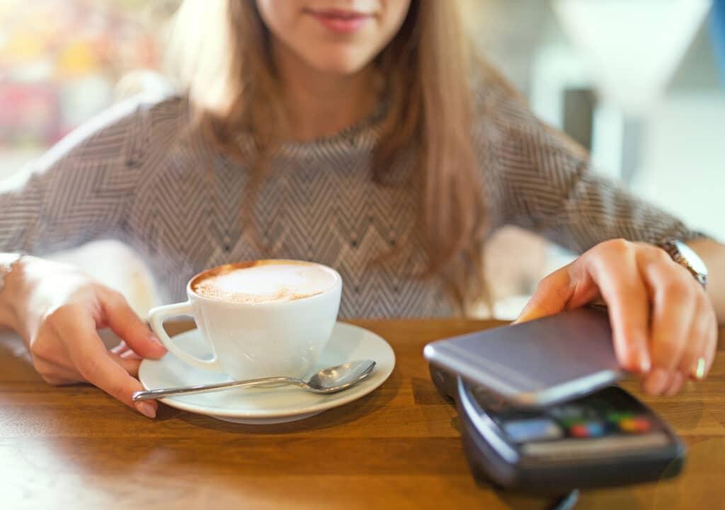 Beste Banken für Nicht-Einwohner: Frau bezahlt Café mit Handy