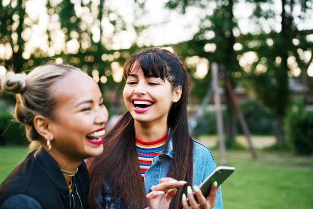 Two girls laughing with a cell phone in hand