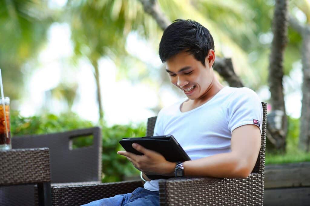 Sort code: person happily using his tablet while sitting at an outdoor restaurant