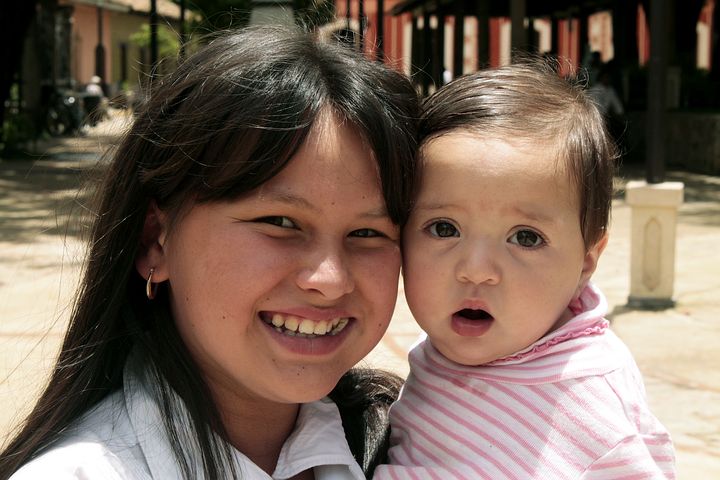 Una joven sonriente con un bebé en brazos