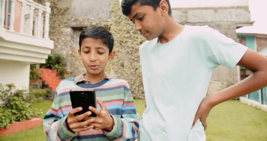 Two young boys look at a cellphone screen