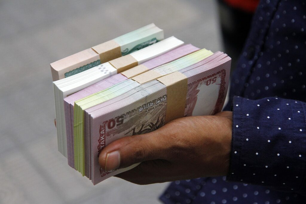 Bangladesh currency: person holding a lot of Bangladeshi takas