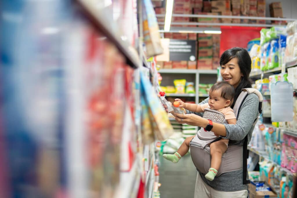 Mother carrying her child while shopping at a grocery store