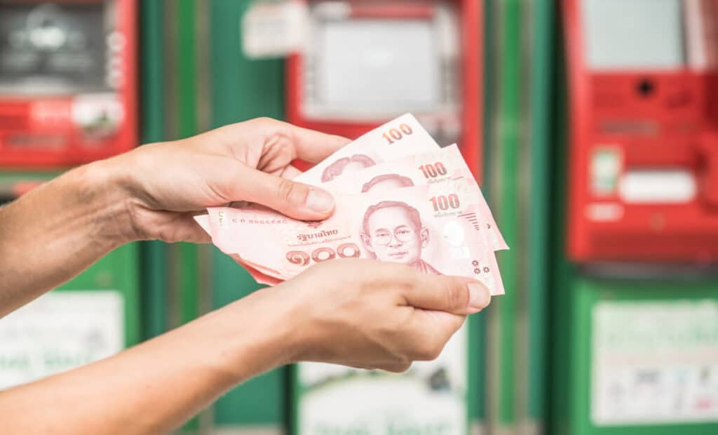 Person holding some Thai Baht bills