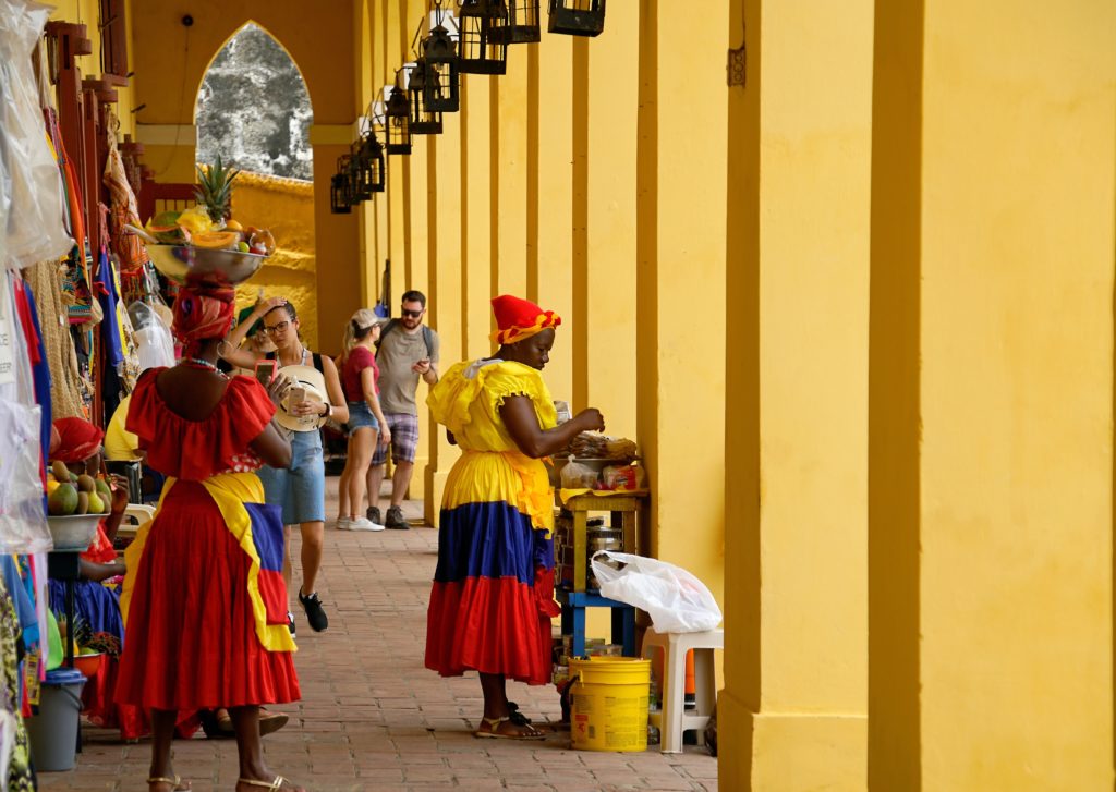 Mujeres en un mercado con vestidos con los colores de la bandera colombiana.