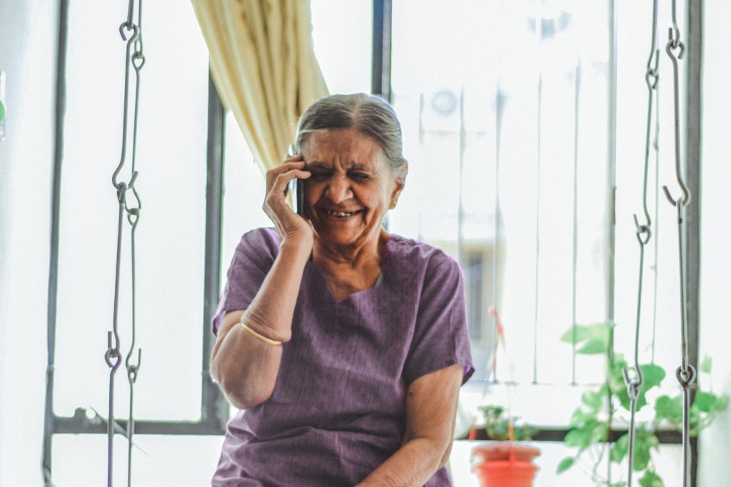 Una anciana riendo y hablando por teléfono