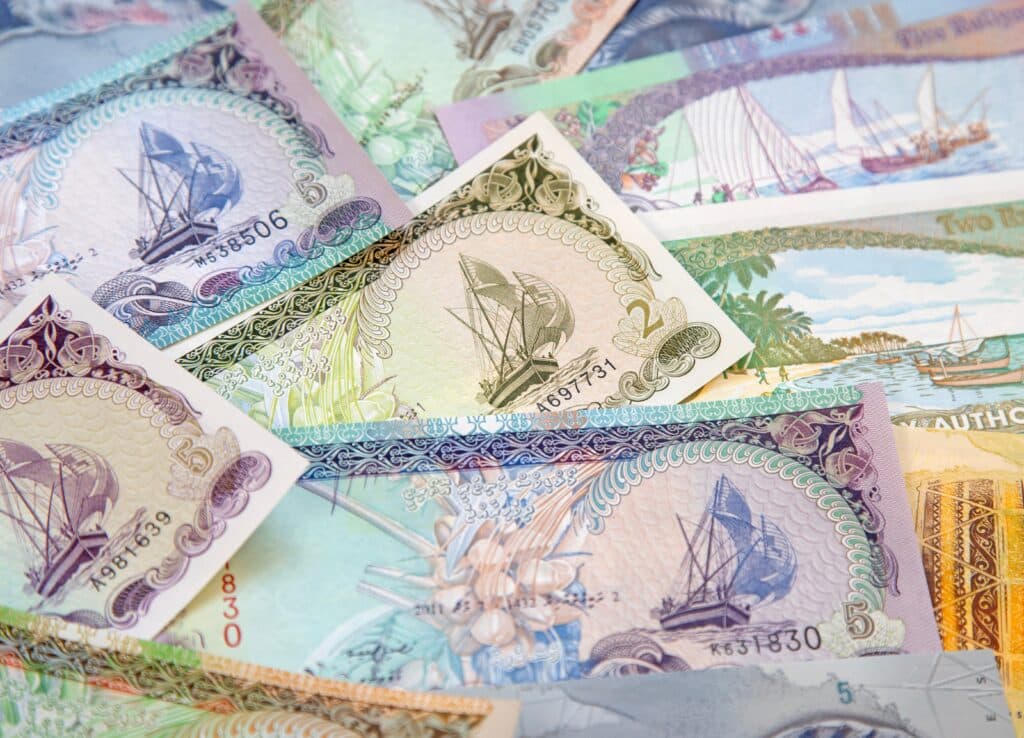 Maldives currency rufiyya bills in a pile featuring beautiful currency images of boats