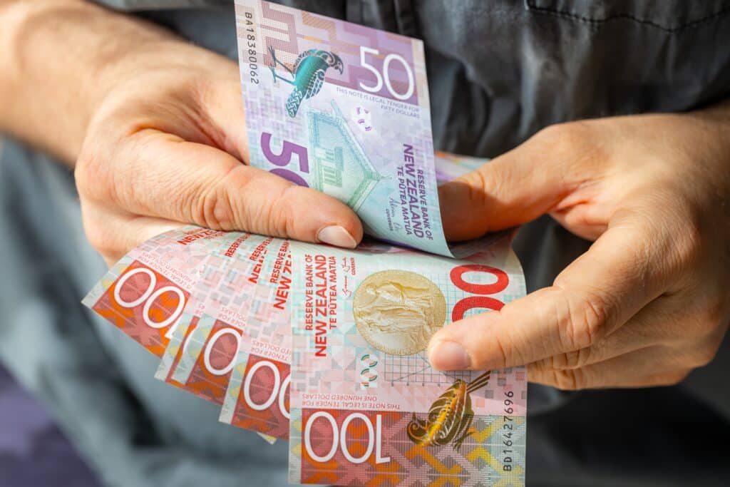 New Zealand dollar notes held in two hands in a list of most beautiful currency in the world