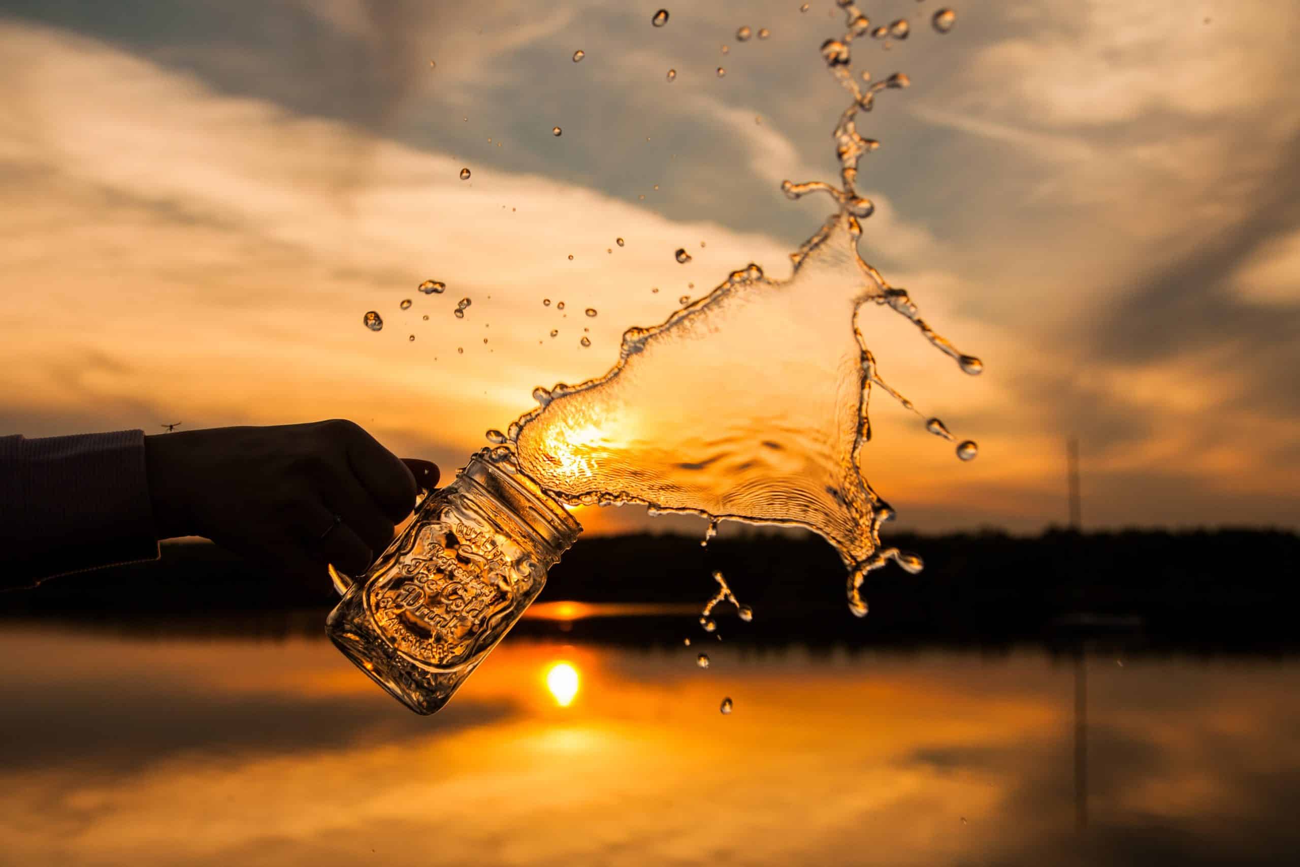 Una mano arrojando agua de un vaso.