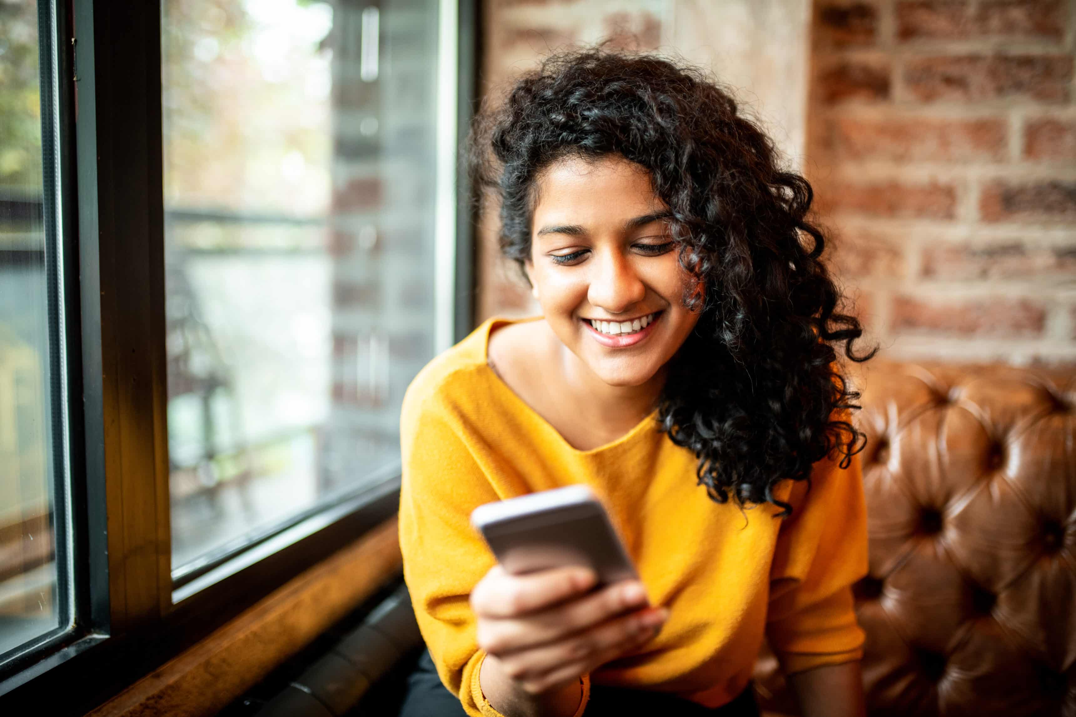 Une jeune femme souriante en utilisant son téléphone portable