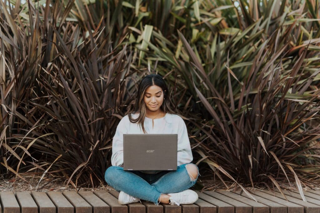 Nebenverdienstmöglichkeiten: junge Frau im Freien mit einem Laptop auf dem Schoß