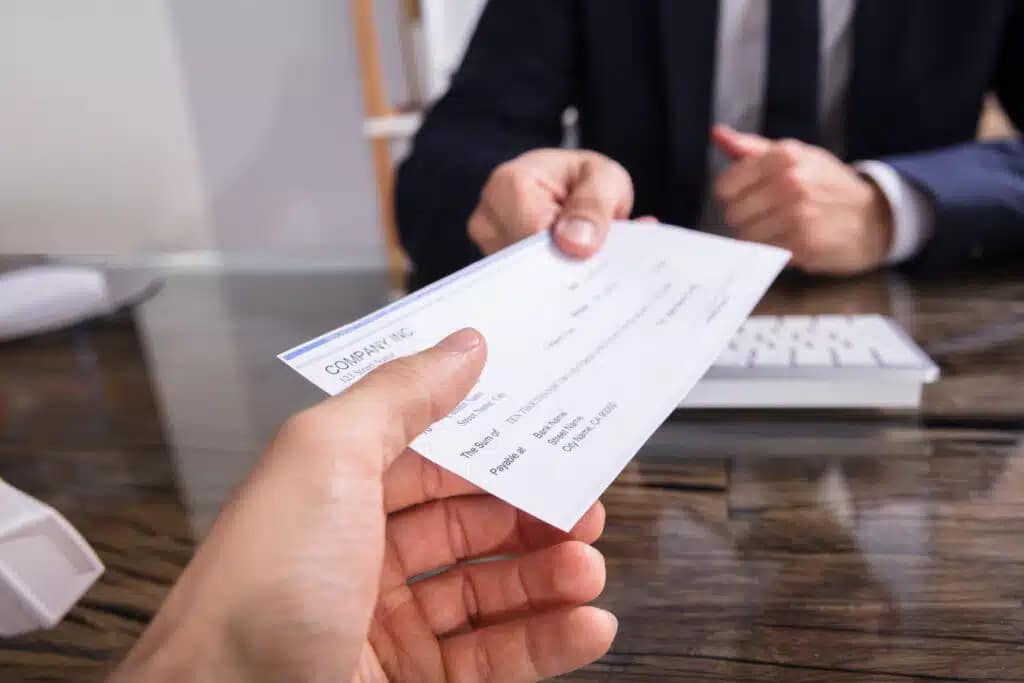 How do you cash checks: person handing a check to a bank personnel