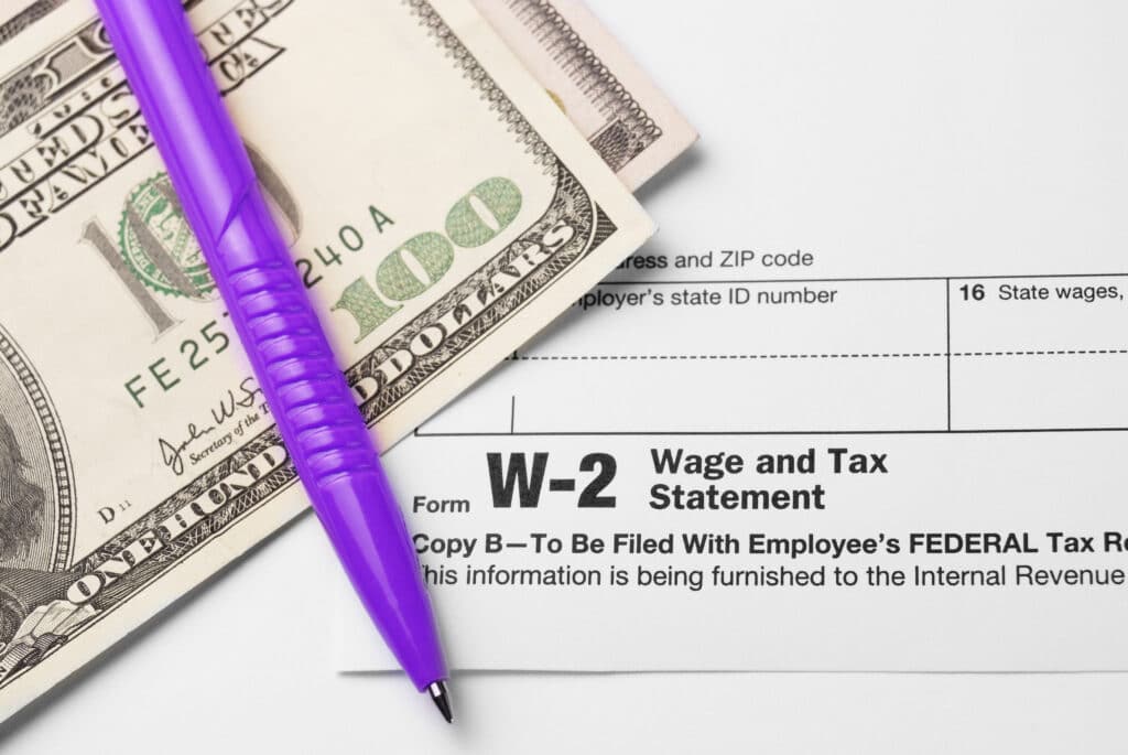 Formulaire de déclaration de revenus avec des billets de 100 USD et un crayon
