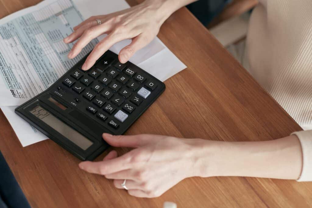 Una mujer haciendo sus cuentas en una calculadora.