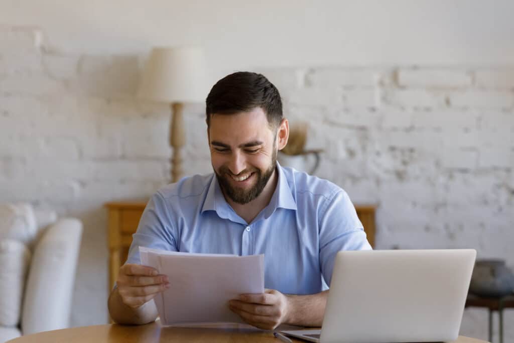 Un homme souriant en lisant des papiers
