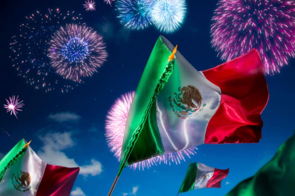 Día de la Independencia de México: banderas mexicanas y fuegos artificiales de fondo