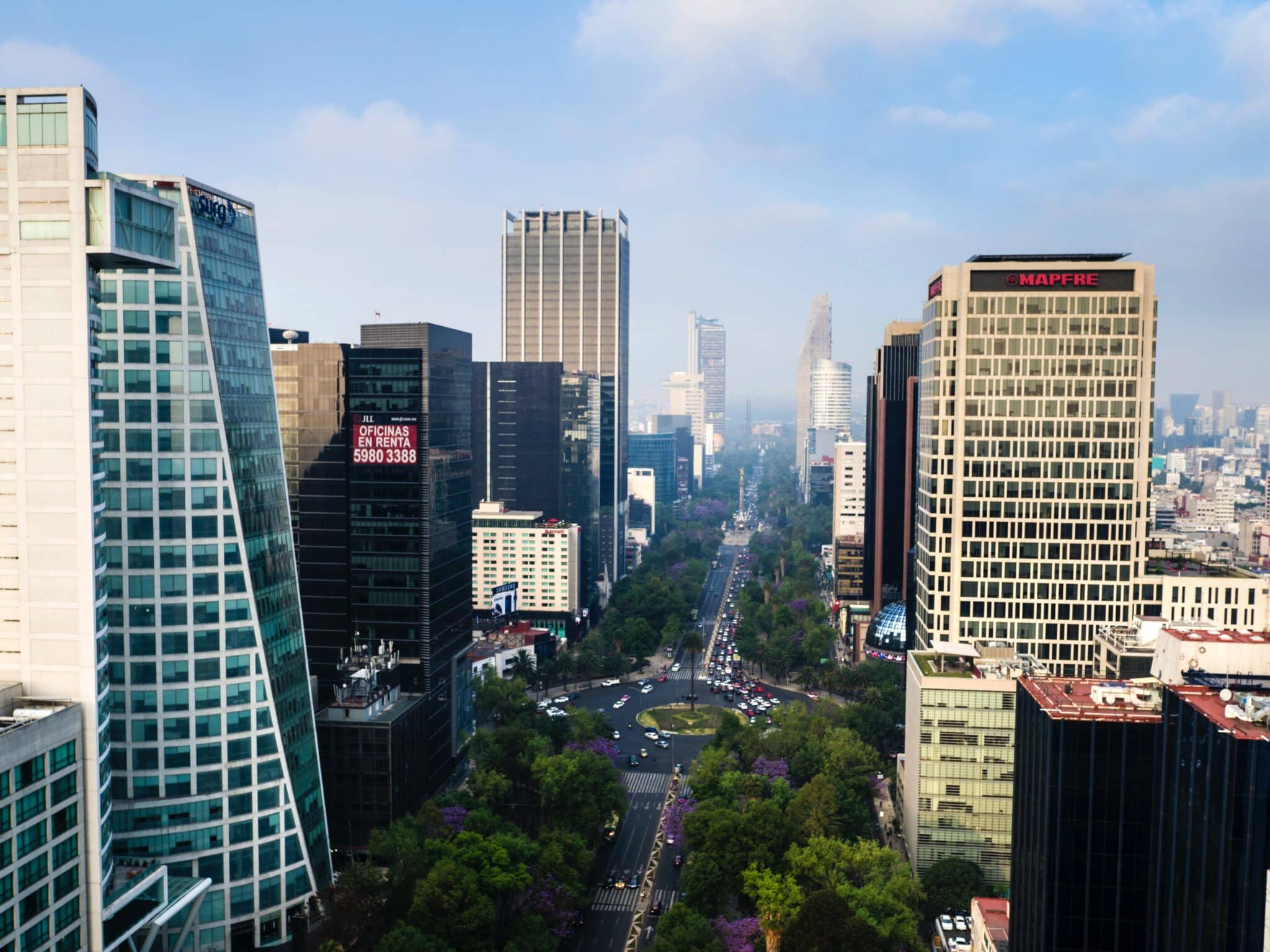 Aerial view of a city skyline with tall buildings and a busy avenue lined with trees.