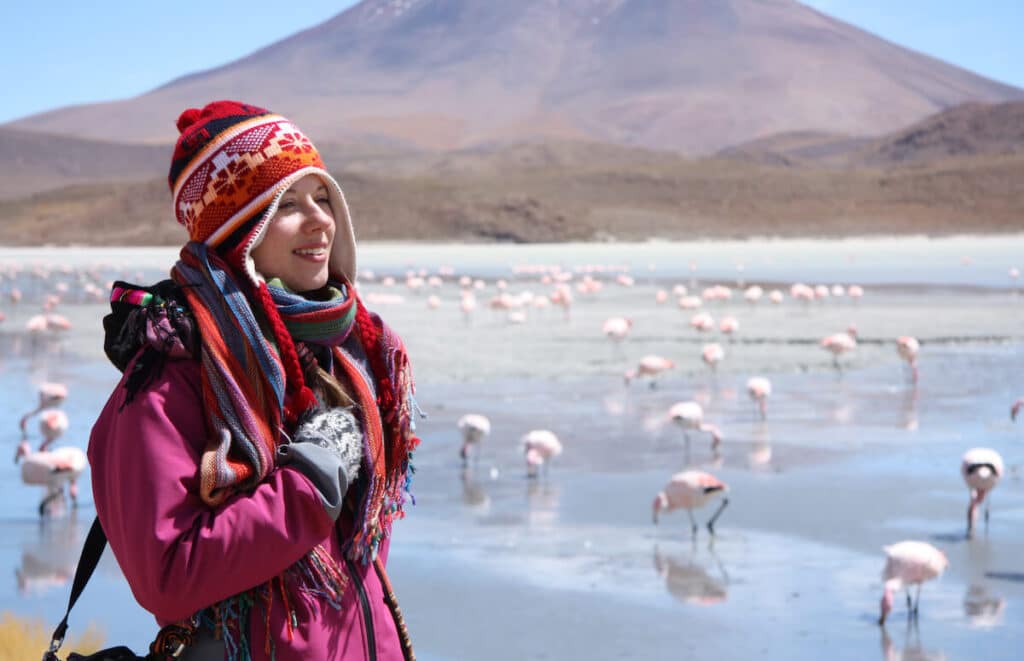 Bolivia currency: woman walking across a group of flamingos