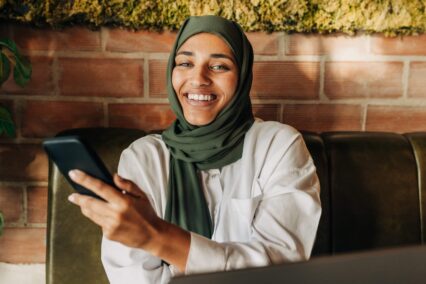 Happy businesswoman with a hijab smiling at the camera in a cafe