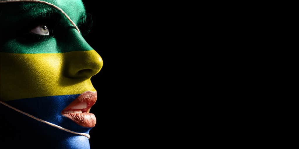 Gabon currency: A person's face painted in green, yellow, and blue like the Gabon flag