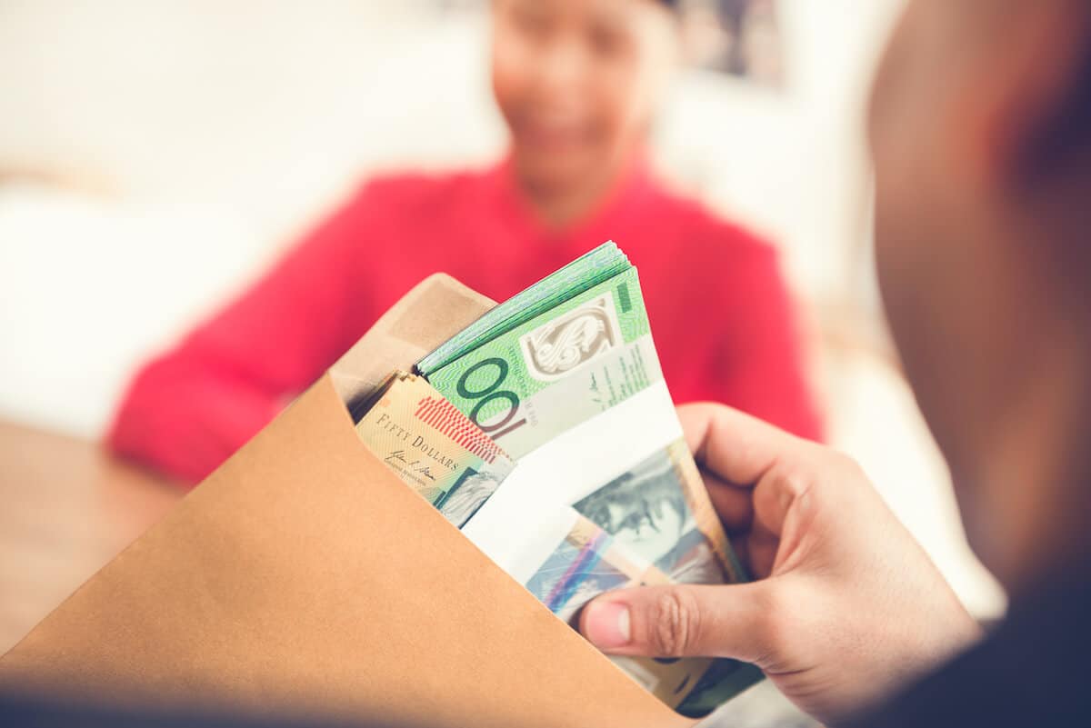 Une personne mettant une somme de dollars australiens en espèce dans une enveloppe