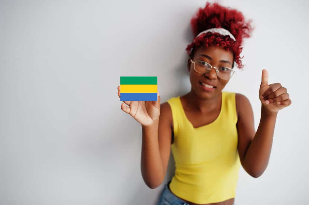 A smiling woman holds a small Gabon flag