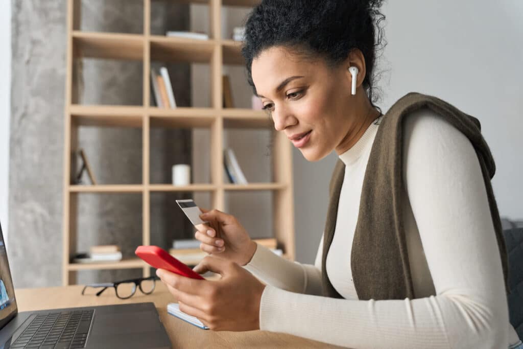 Woman using her phone and holding a credit card