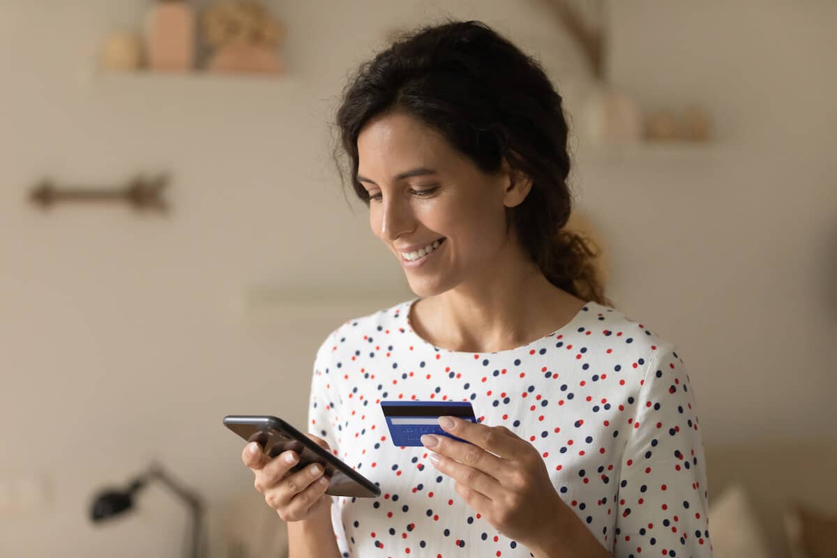What is a money order: woman using her phone and holding a credit card