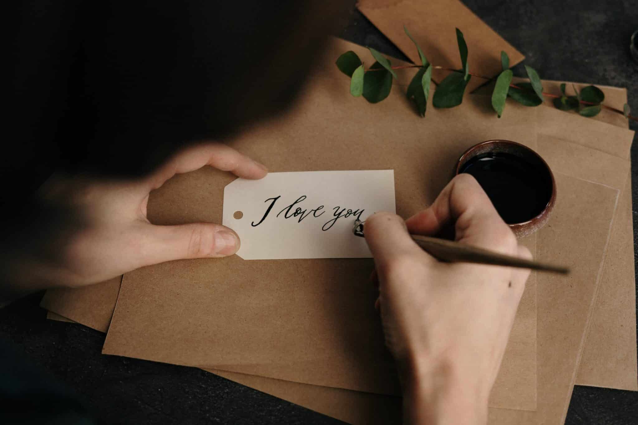 Primer plano de las manos de una persona escribiendo una nota de amor