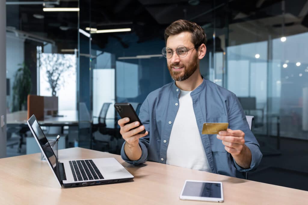 Man using his phone while holding a credit card