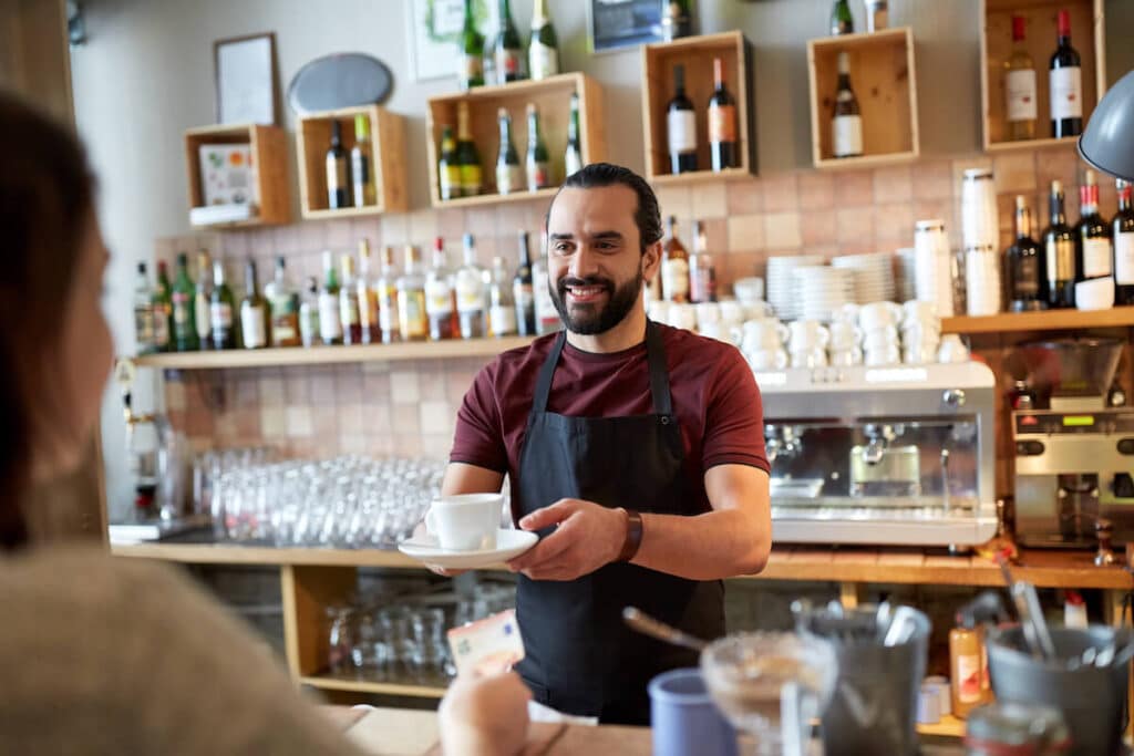 Waiter handing a cup of coffee to a customer