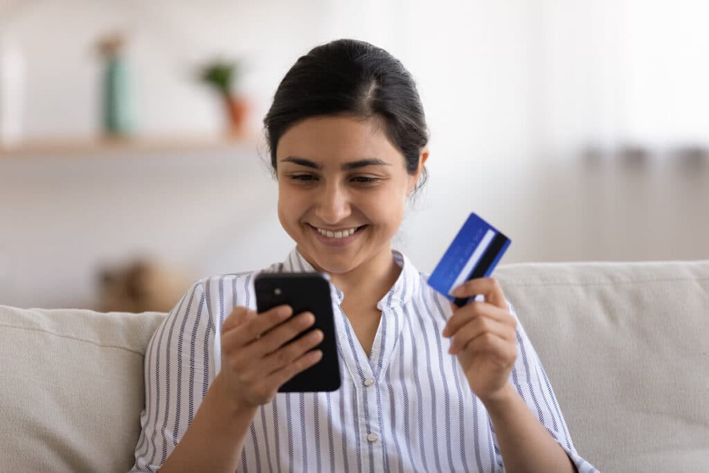 Woman using her phone while holding a credit card