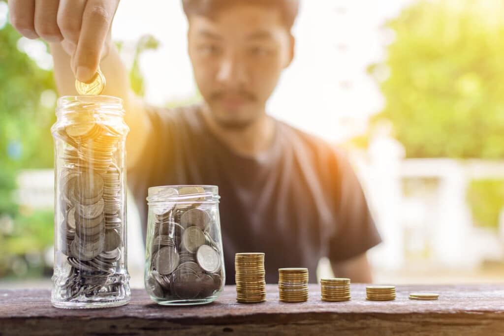 Cost of living in Philippines: man putting coins into glass jars