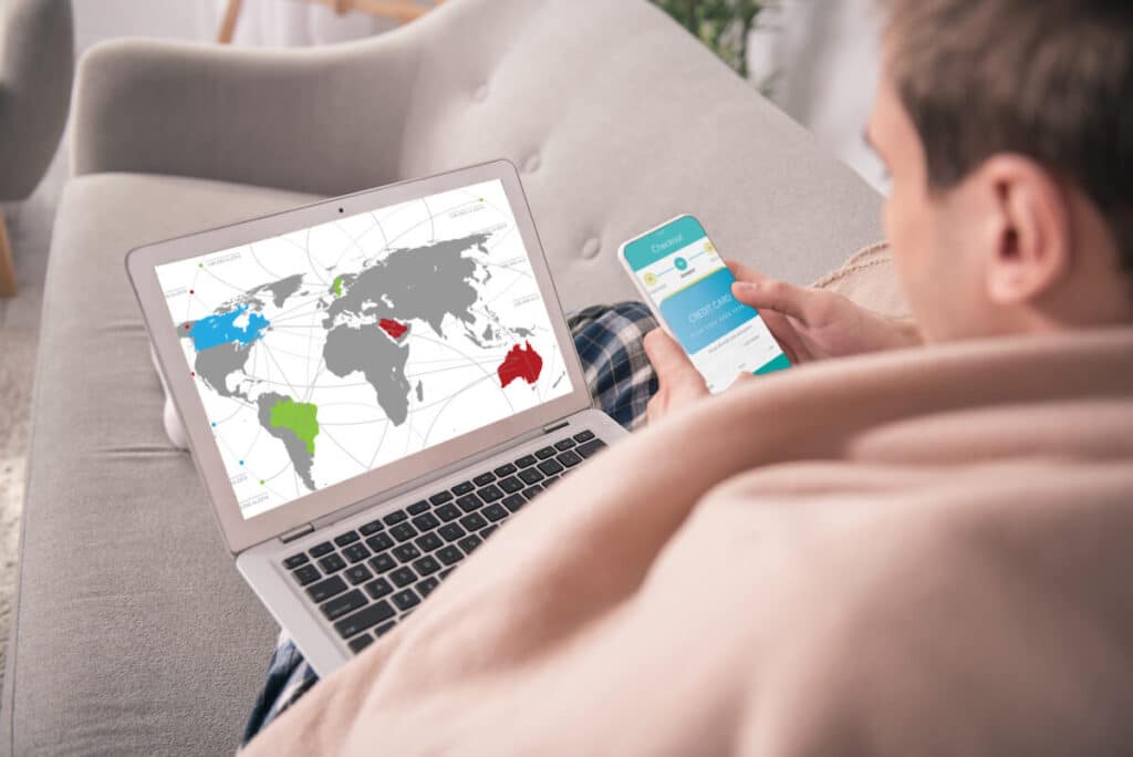 Überweisungslimits: Person mit Laptop, er eine Weltkarte zeigt