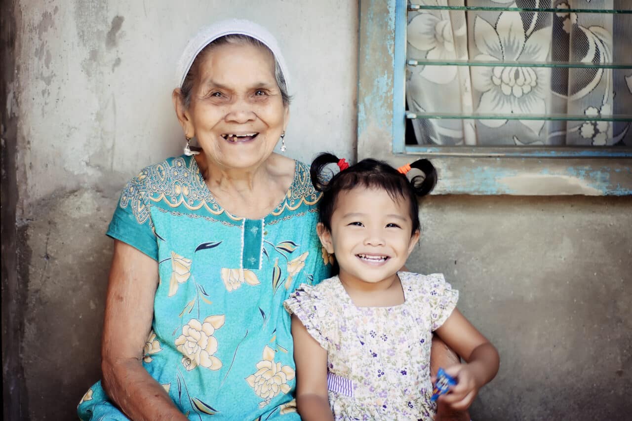 Grandmother and granddaughter sitting together smiling for a photograph 