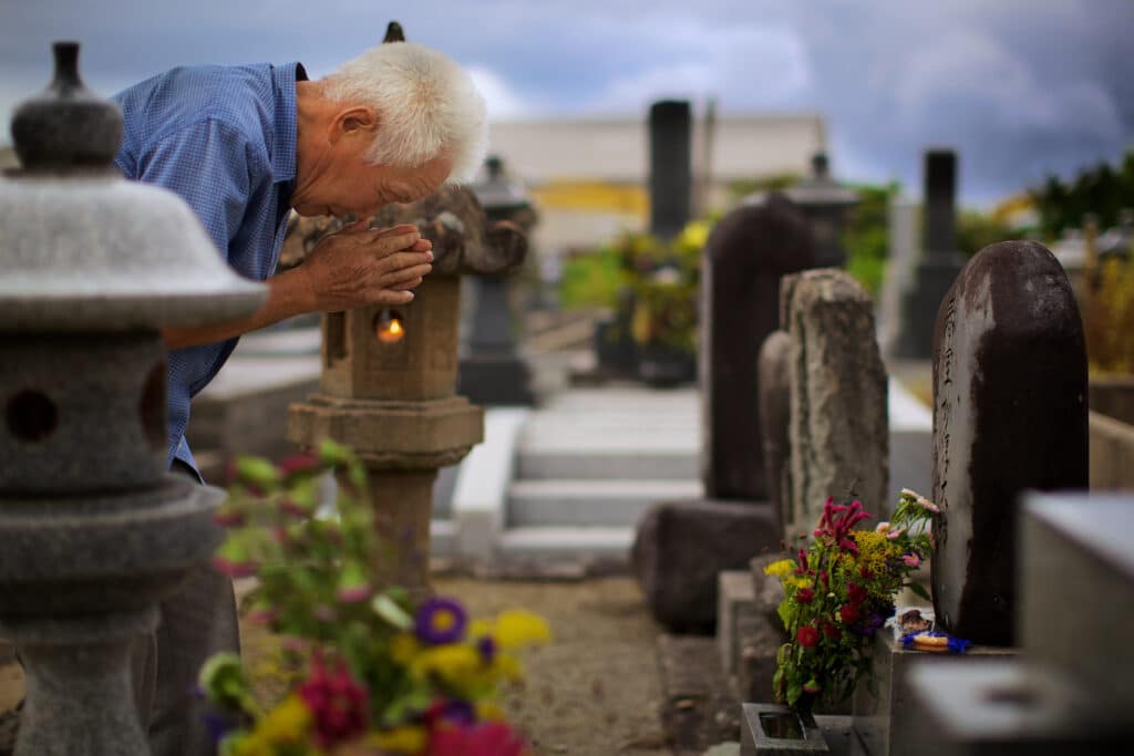 Durante il festival Obon in Giappone, un anziano rende omaggio ai suoi antenati in un cimitero locale di quartiere.