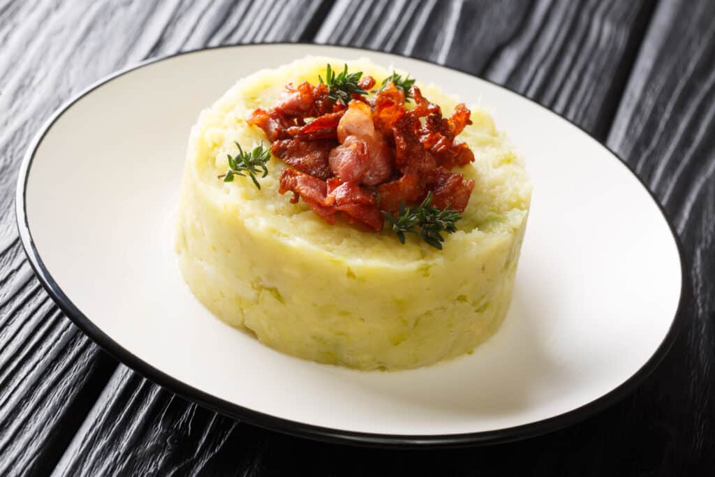 Tasty Trinxat mashed potatoes and green cabbage with fried bacon closeup in a plate on the table. horizontal, Andorra national dish