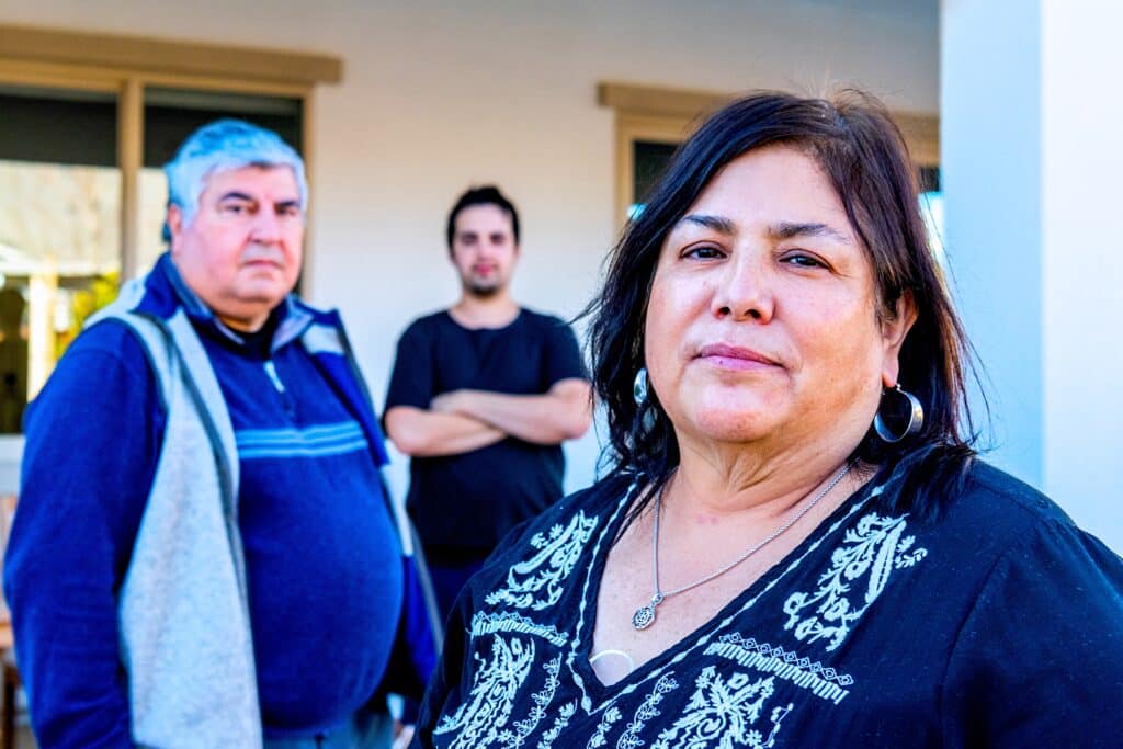 Hispanic family, mother, father and son posing outside their backyard looking at the camera