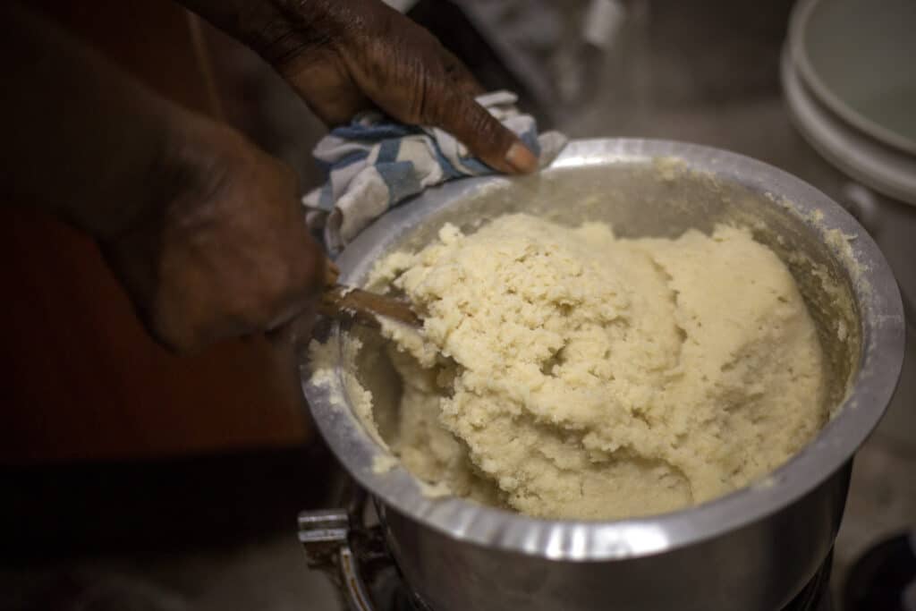 African woman preparing common ugali made from maize flour. Ugali also called nsima.