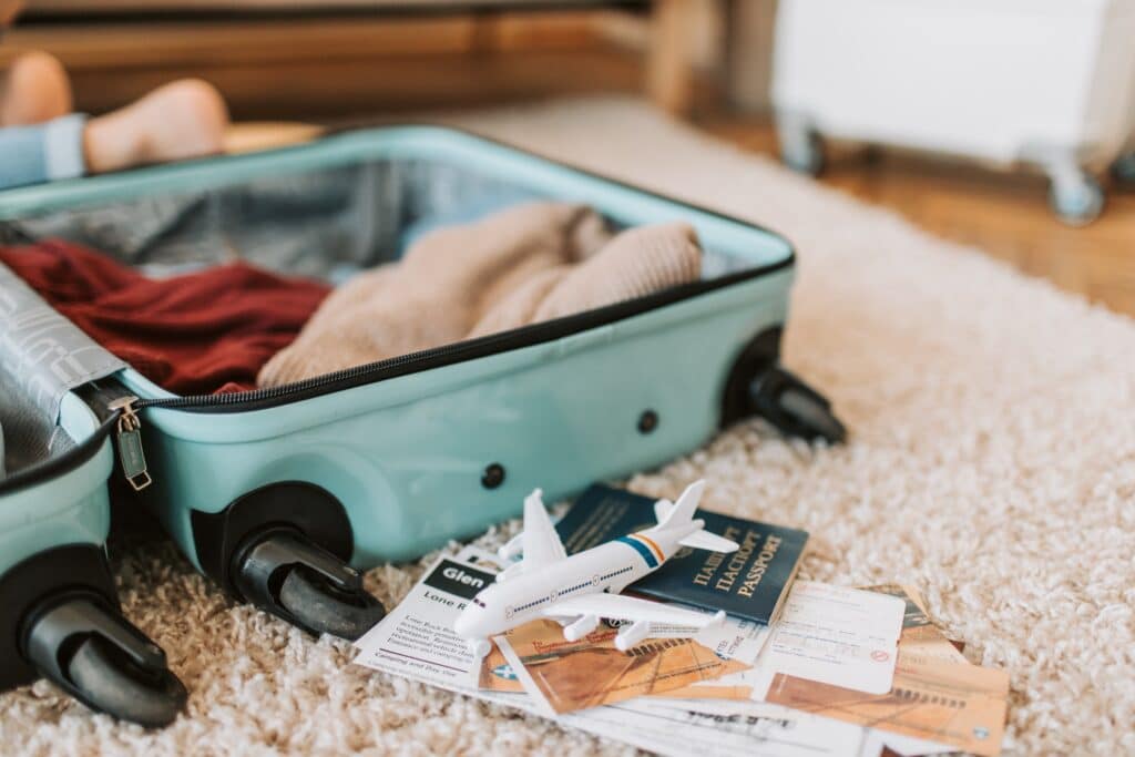 Un passeport sous un avion miniature à côté d'une valise