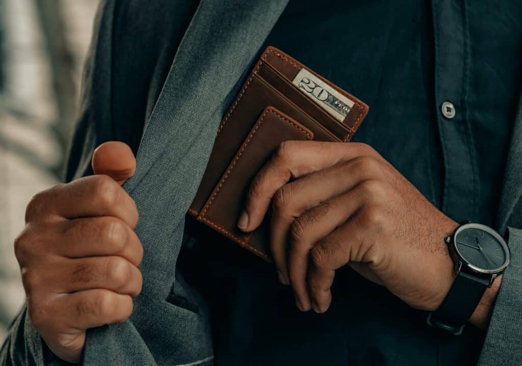 Un homme mettant un portefeuille comportant 20 USD dans sa poche de veste