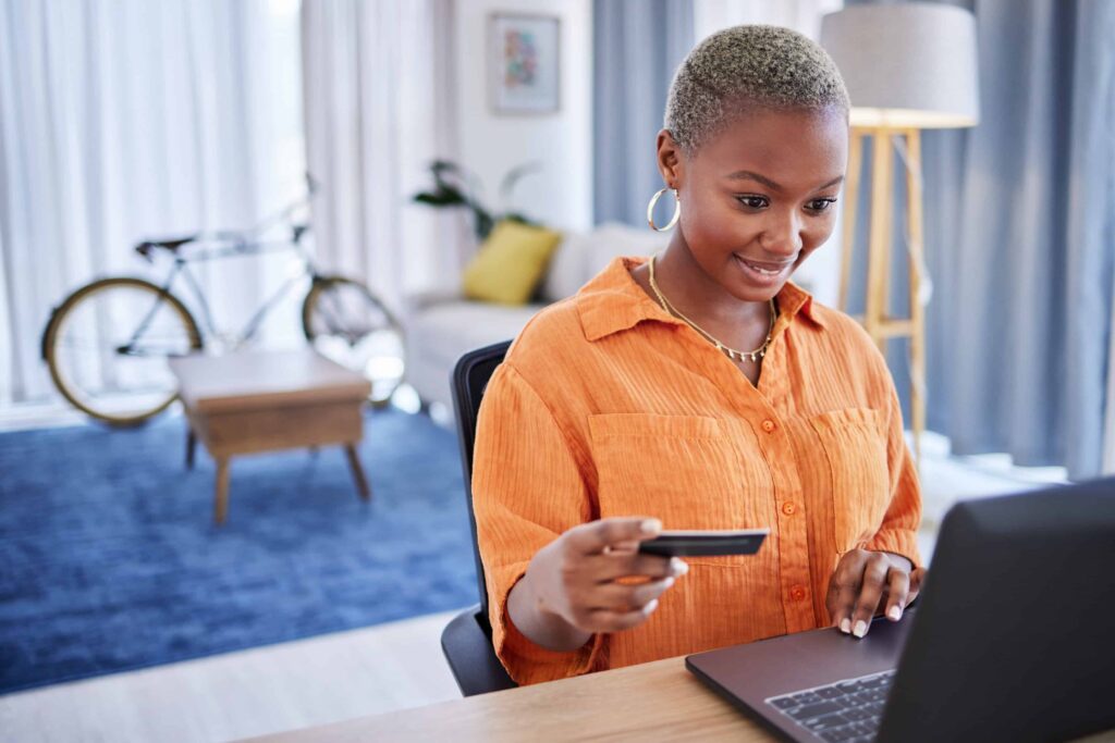 Excited, laptop or black woman with credit card in home for ecommerce sale on digital fintech website. Finance, payment discount or happy girl online shopping or banking on internet typing in data