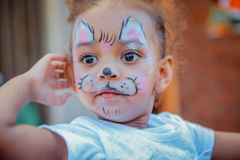 young girl with halloween face paint on that looks like a cat