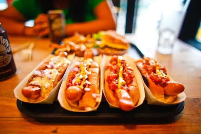 Four hot dogs with sauce and toppings on a table