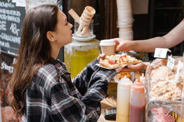 Woman buying waffles from a street food vendor