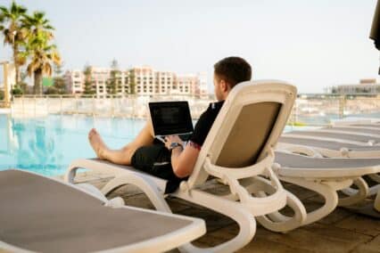 A man sitting in a pool chair while working on his computer